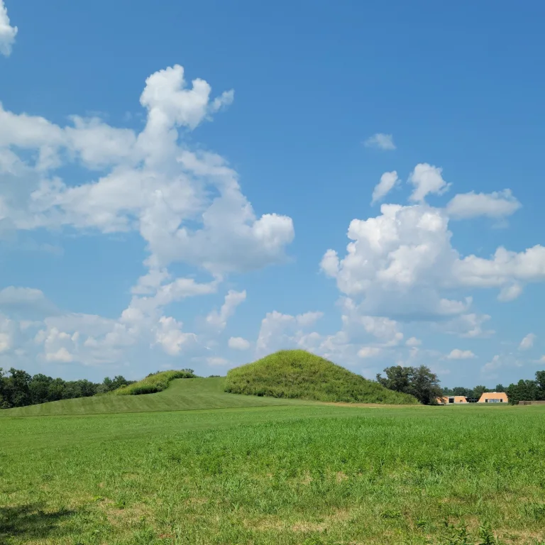 Central mound and connected earthworks at Angel Mounds State Historic Site, with mown green slopes and blue sky in the background.