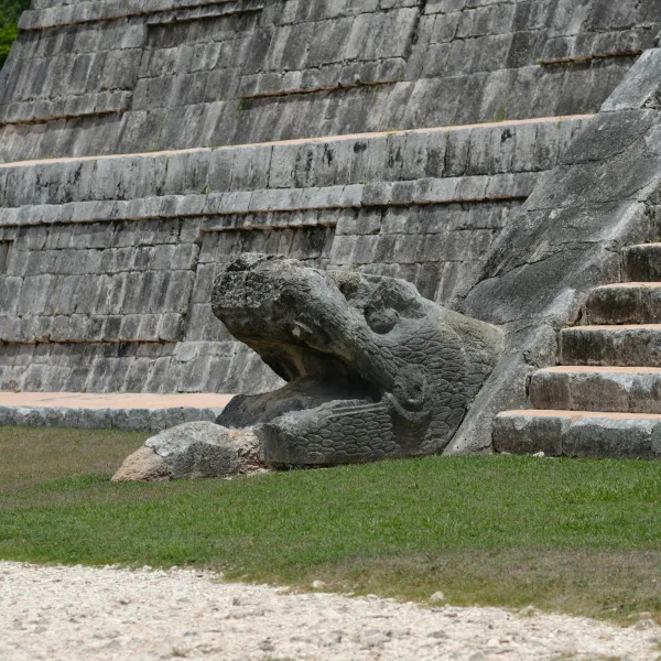 Stone serpent head carving at the foot of El Castillo in Chichén Itzá, symbolizing the feathered serpent god Kukulkan