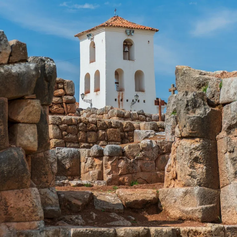 White colonial-era church bell tower rising above original Inca stone foundations at Chinchero, Peru.