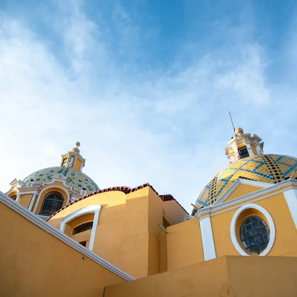 Close-up view of the blue-and-yellow tiled domes of the Church of Nuestra Señora de los Remedios under a clear sky