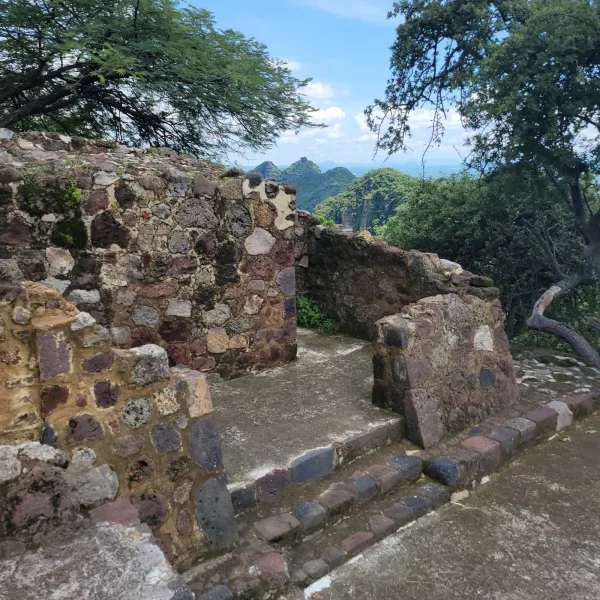 View from El Tlatoani temple ruins overlooking green cliffs and distant ridges of the Tepoztlán valley