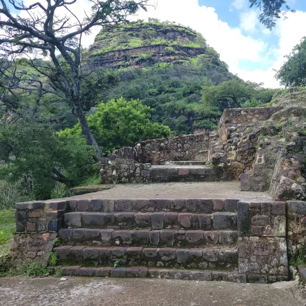 Stone platform at the top of El Tlatoani with ruins in the foreground and the mesa behind