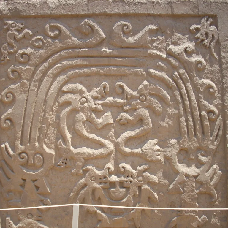 Carved adobe frieze of mythological figures and rainbows at El Dragón Huaca Arco Iris temple in Trujillo Peru