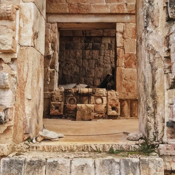 Close-up of a stone doorway at Kabah featuring a carved Chaac rain god face at its base, part of the Puuc Route in Yucatán, Mexico.