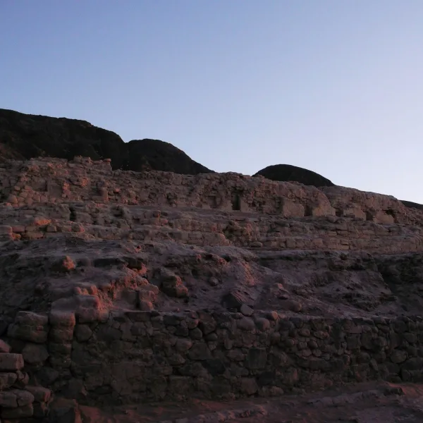Multi-level Inca stone construction at Los Paredones glowing with late-day light beneath a darkening sky