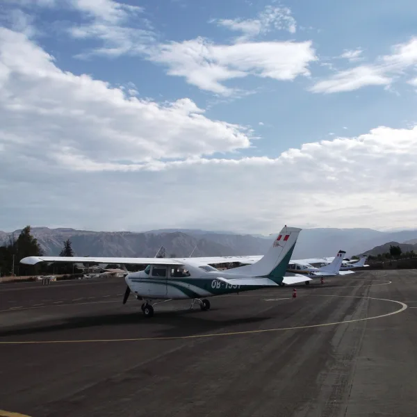 Ground photo of small tour planes lined up at Nazca Airport with the Andean mountains in the background