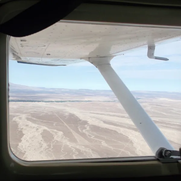 Aerial photo of the Nazca desert showing long straight geoglyph lines viewed from a small aircraft window