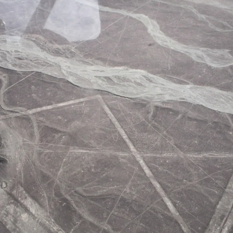 Aerial view of the Nazca Sunfish geoglyph etched into the desert plateau, with geometric rays extending from its body across the surrounding landscape