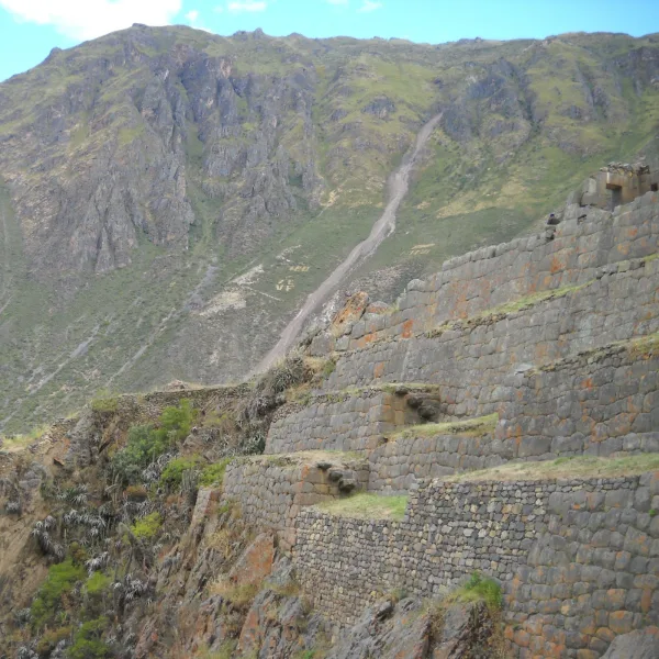Angled view of Inca terraces on Temple Hill at Ollantaytambo with mountain backdrop and stone construction detail.