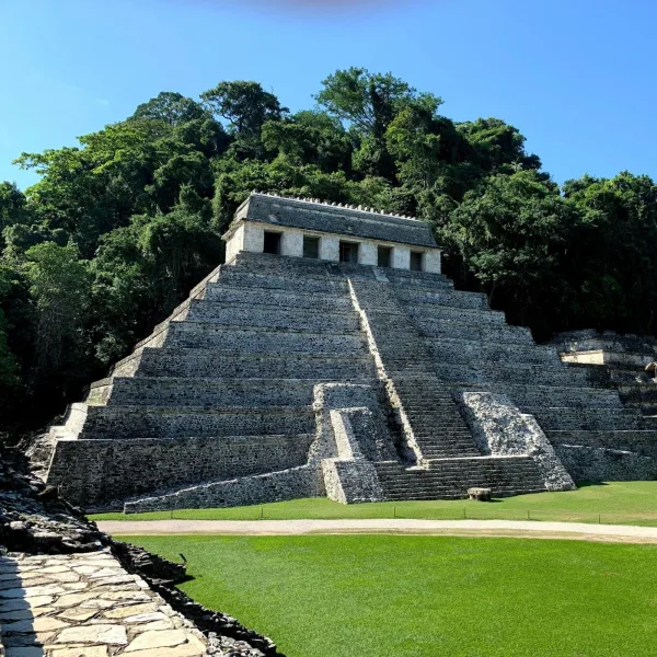 Front view of the Temple of the Inscriptions at Palenque, the funerary pyramid of Pakal the Great, set against a forested hillside.