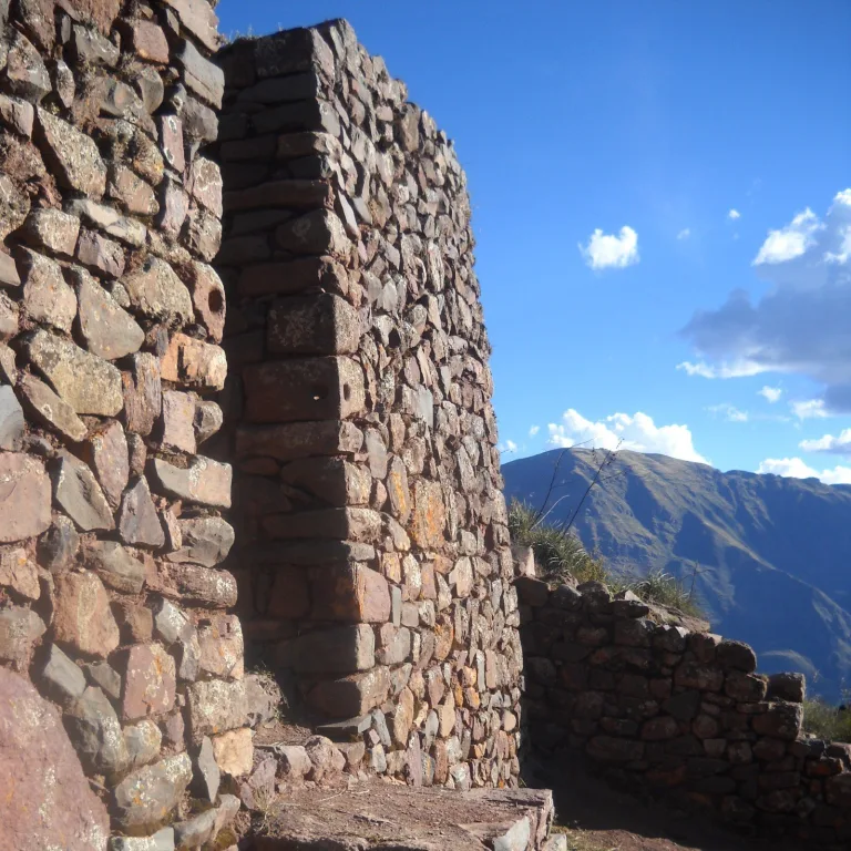 Stone doorway and carved steps at Pisac ruins, framed by Inca walls and looking out over the Sacred Valley mountains