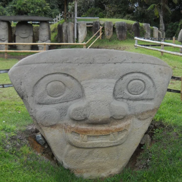Broad stone head with fangs and round eyes from San Agustín, Colombia, representing a supernatural or hybrid figure
