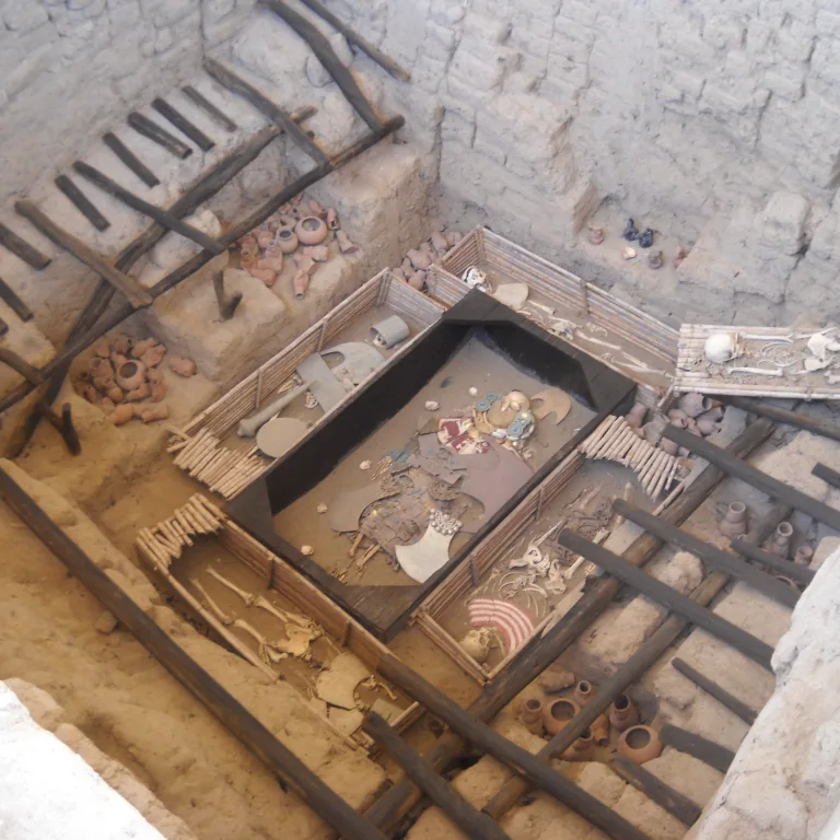 Detailed view of the Lord of Sipán’s tomb, with gold and silver regalia, human remains of attendants, and reconstructed burial layout in an adobe-walled pit.