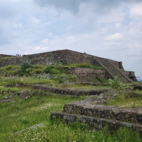 Stone temple platform at Teotenango archaeological site, with visitors standing on top, showcasing the site's defensive elevation and preserved architecture.