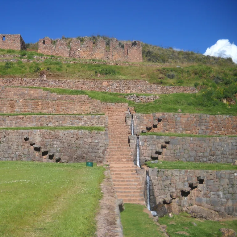 Stair-stepped terraces and cascading Inca aqueduct system beneath hilltop ruins at Tipón
