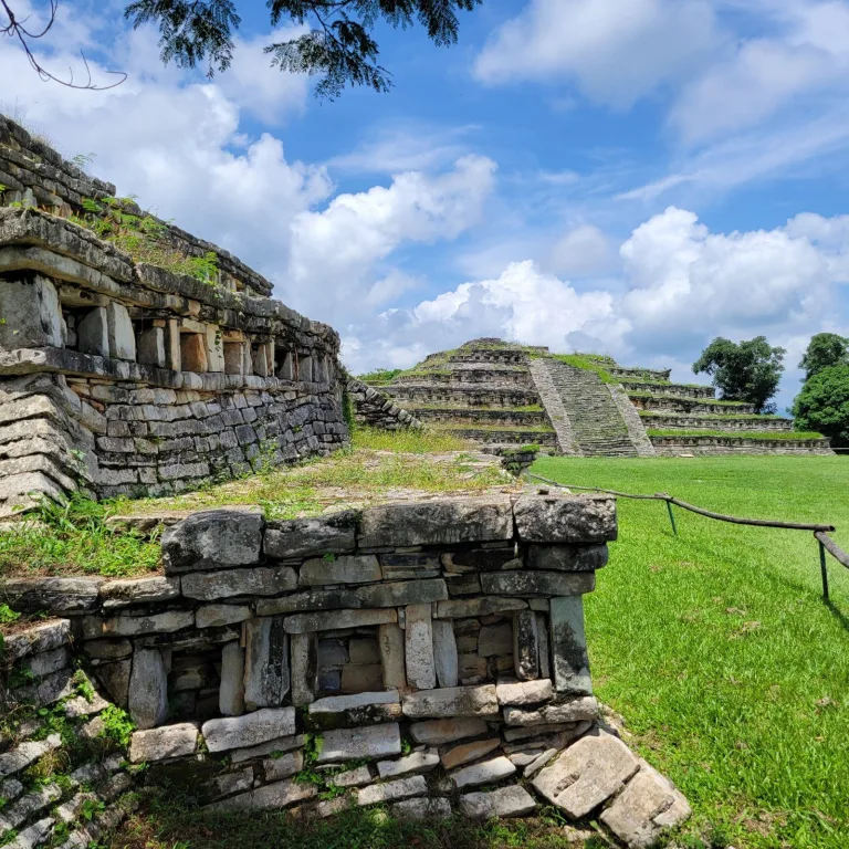 Broad stone staircase climbing one of the main platforms at the Yohualichan ruins, framed by cut grass and clear skies.