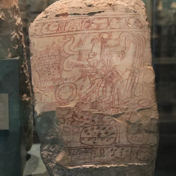 Ancient Maya stela with red pigment carvings depicting a royal figure and hieroglyphs at Calakmul
