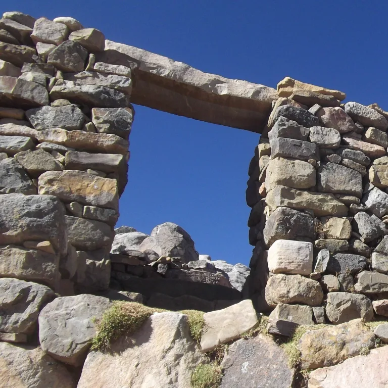 Ancient stone gateway at the Chincana Labyrinth ruins on Isla del Sol, Bolivia, under a clear blue sky.