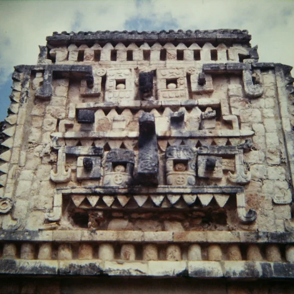 Detailed view of rain god Chaac mask and intricate mosaic stonework on Puuc-style building at Xlapak