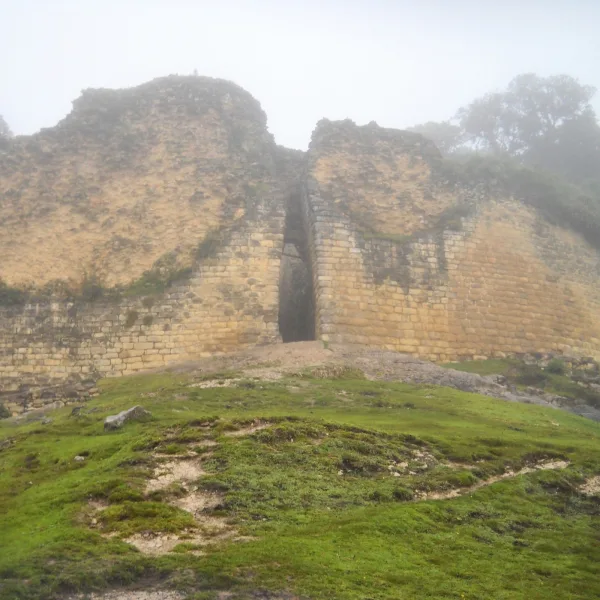 Fog-covered stone entrance of the Kuelap fortress in northern Peru with steep Chachapoya defensive walls.