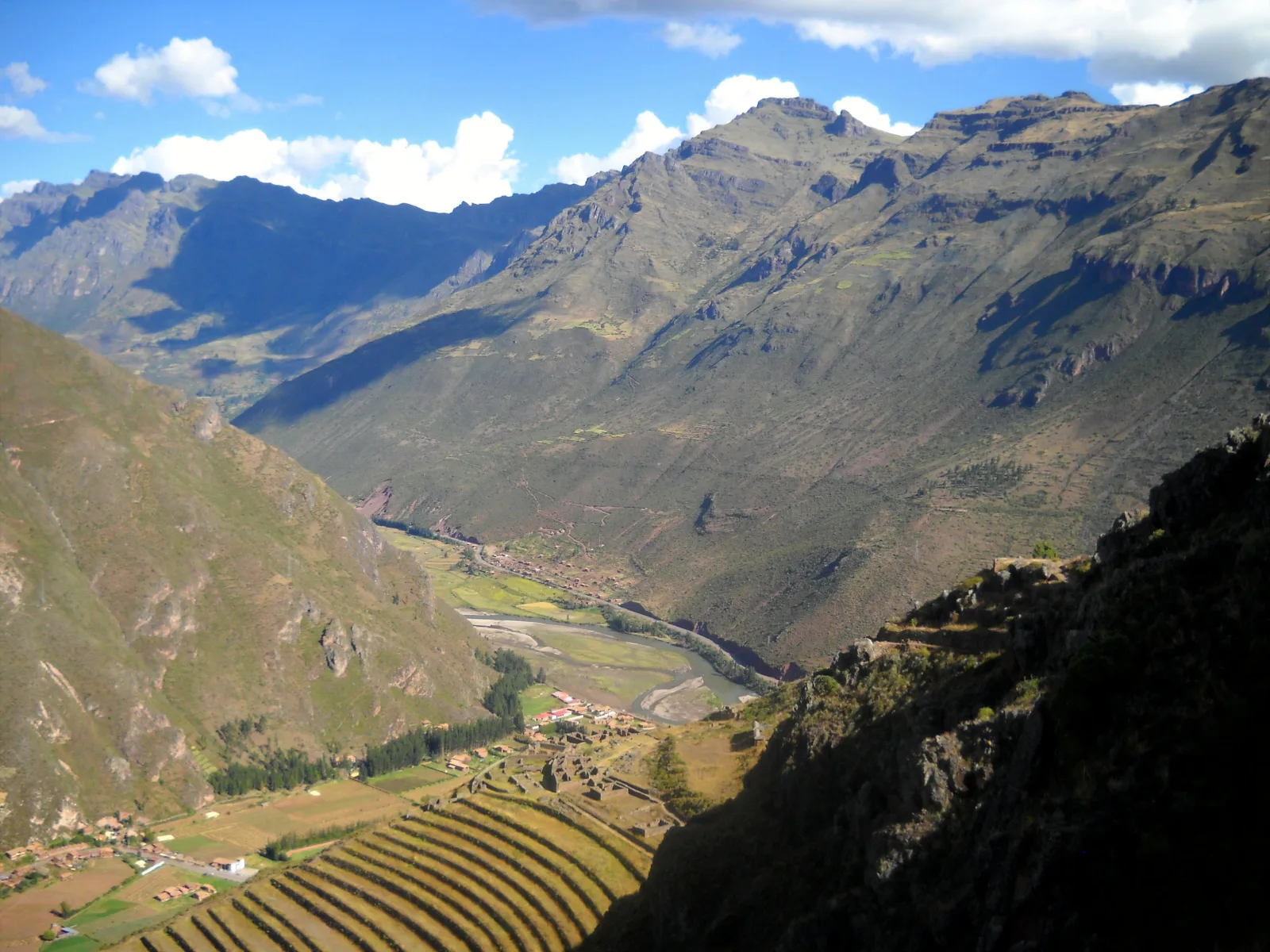 View of the Sacred Valley of the Incas from Pisac, showing terraced slopes, Urubamba River, and surrounding Andean mountains in Peru.
