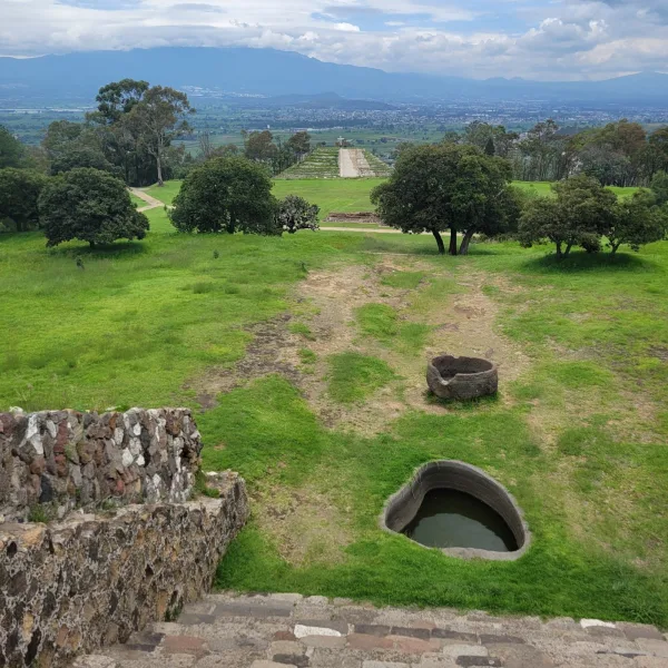 View of ceremonial stone Carved stone ritual basins positioned below the summit of the Basamento de los Volcanes at Xochitécatl, partially enclosed by terraced walls