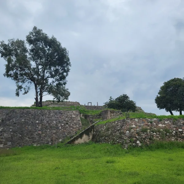 Stone terraces forming the approach to the Basamento de los Volcanes at Xochitécatl, with a ceremonial arch standing at the summit