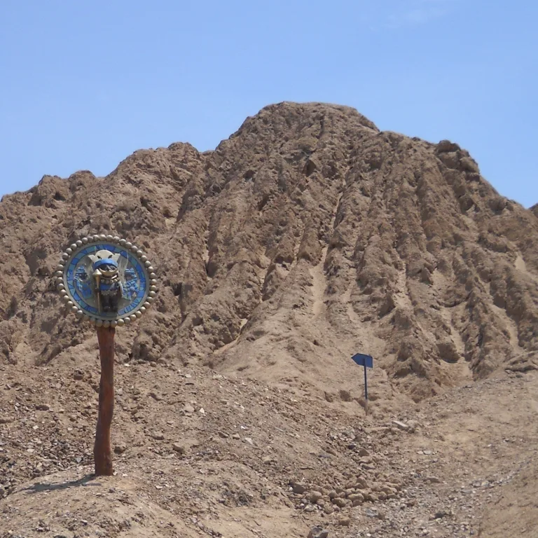 Circular emblem marking the tomb of the Lord of Sipán at Huaca Rajada in Lambayeque, Peru, with the eroded Moche pyramid mound behind