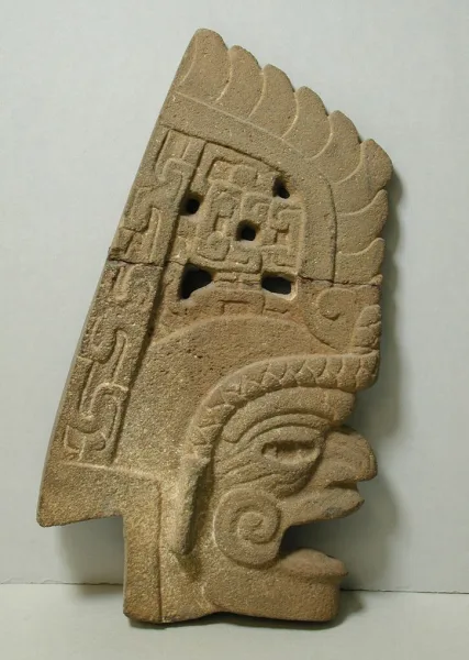 Classic Veracruz stone hacha sculpture carved in the shape of a profile head with elaborate feathered headdress, used for ceremonial display or as a ballgame marker.