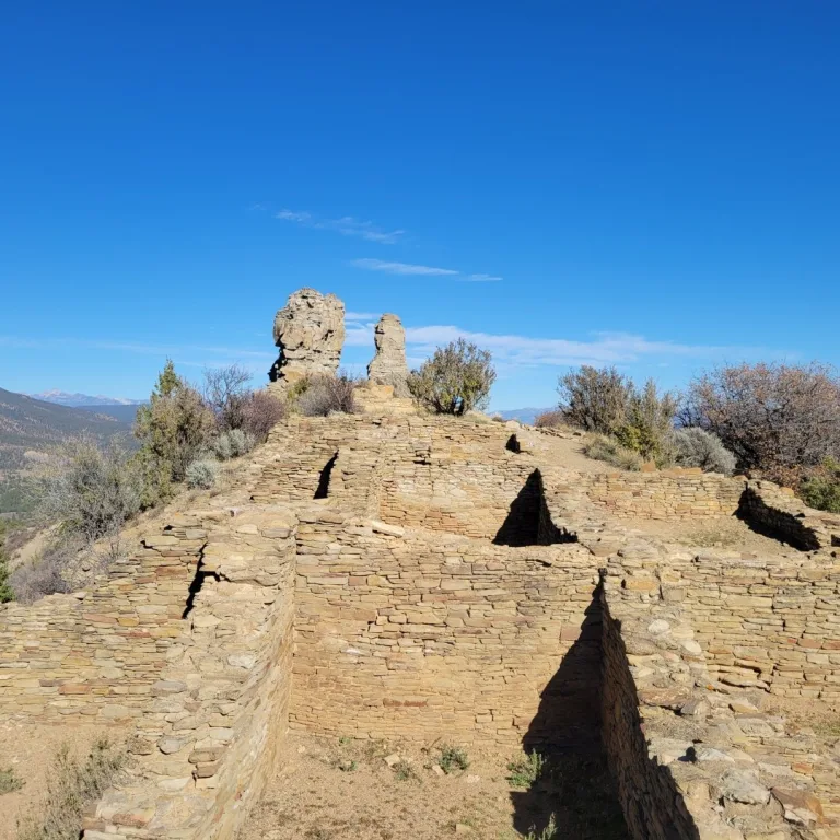 Ruins of a room block sit on the mesa top below the two iconic, distinct rock spires known as the Chimney Rock and Companion Rock.