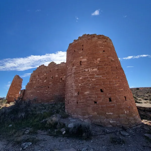 The impressive, multi-story masonry ruins of Hovenweep Castle, featuring two rectangular towers built on the canyon rim against a blue sky.