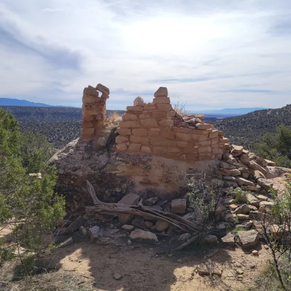 Ridgetop masonry structure at Painted Hand Pueblo, with collapsed sandstone walls overlooking the surrounding high desert landscape.