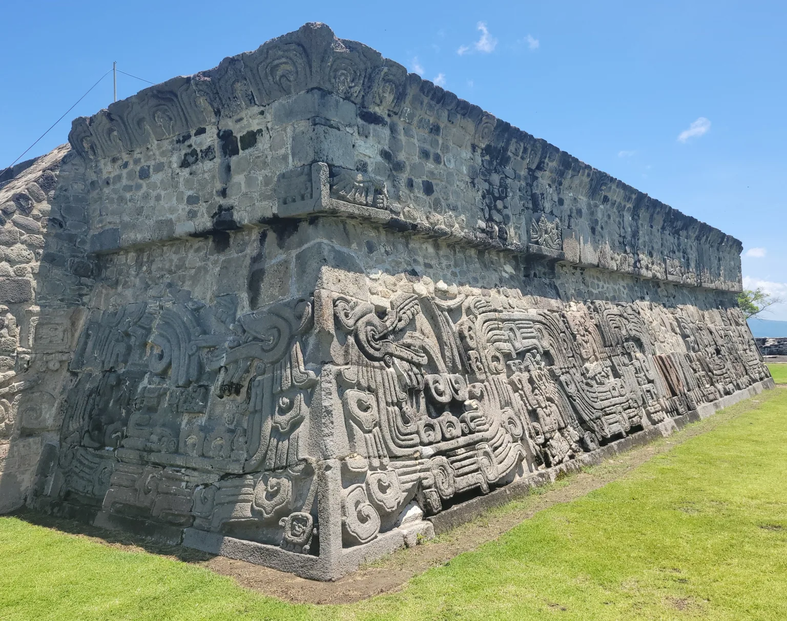Stone relief walls of the Temple of the Plumed Serpent at Xochicalco, showing carved feathered serpent figures and glyph panels on stepped masonry.