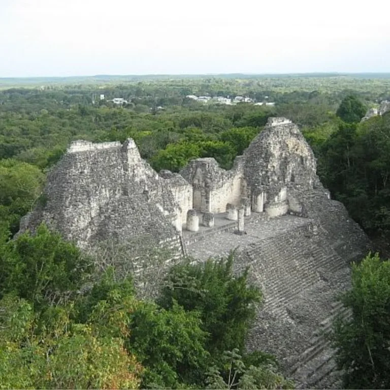 Structure VIII at Becán, a Maya site in Campeche, Mexico, rising above the surrounding forest with steep stone slopes and the remains of a temple at the summit.