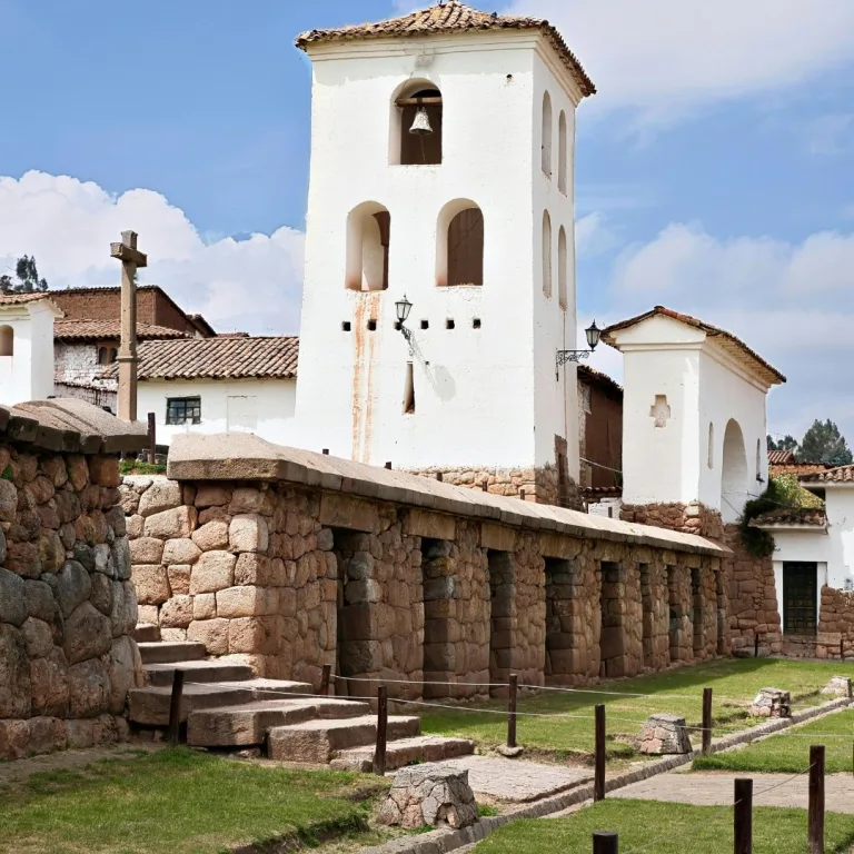 Colonial church at Chinchero built above Inca stone terraces, with white adobe walls, arched openings, and a bell tower.