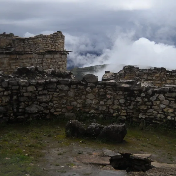 Stone ruins at Kuélap in Chachapoyas, Peru, with low clouds rising behind the walls.