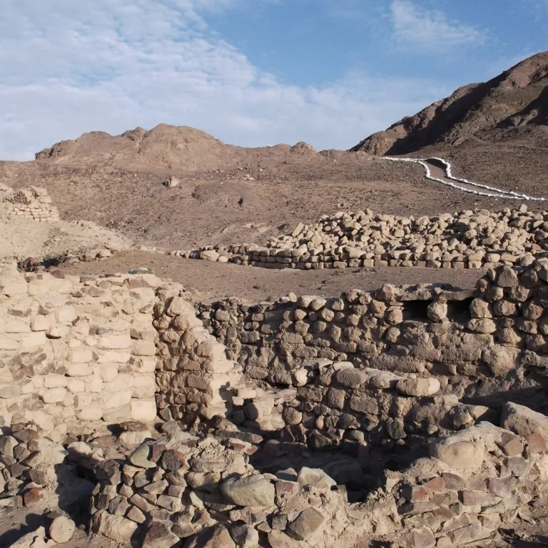 Stone and adobe ruins at Los Paredones near Nazca, Peru, with low wall remains set against a dry mountain landscape.