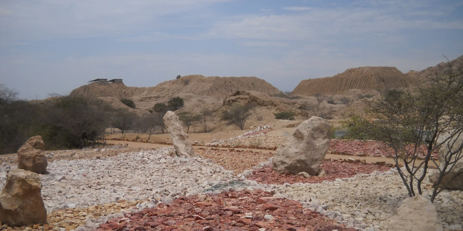 Adobe huacas at Túcume in Lambayeque, Peru, seen from a landscaped visitor area near the site entrance.