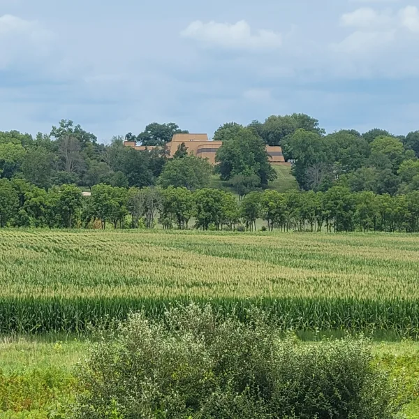 Dickson Mounds Museum in Lewistown, Illinois, seen from a distance across fields and trees from the Ogden-Fettie Mounds area.