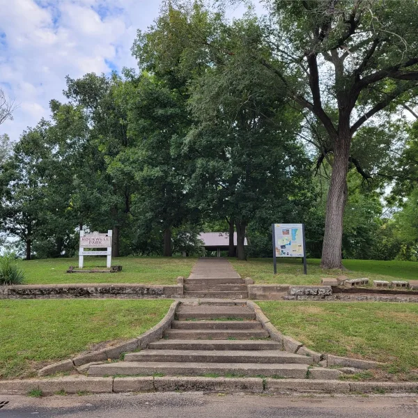 Main entrance to Rockwell Mound in Havana, Illinois, with stone steps leading up the large Havana Hopewell earthwork toward a shelter beneath mature trees.