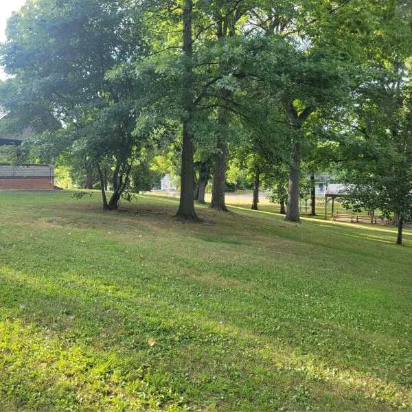 Rockwell Mound in Havana, Illinois, with a side view across the grassy top of the large Havana Hopewell earthwork, mature trees, and a park shelter.