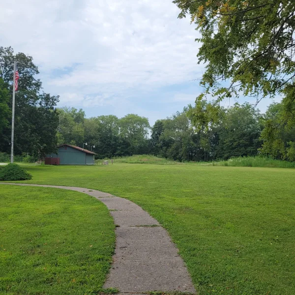 Toolesboro Mounds in Iowa, with a sidewalk, visitor building, open lawn, trees, and a mound visible beyond the parking area.