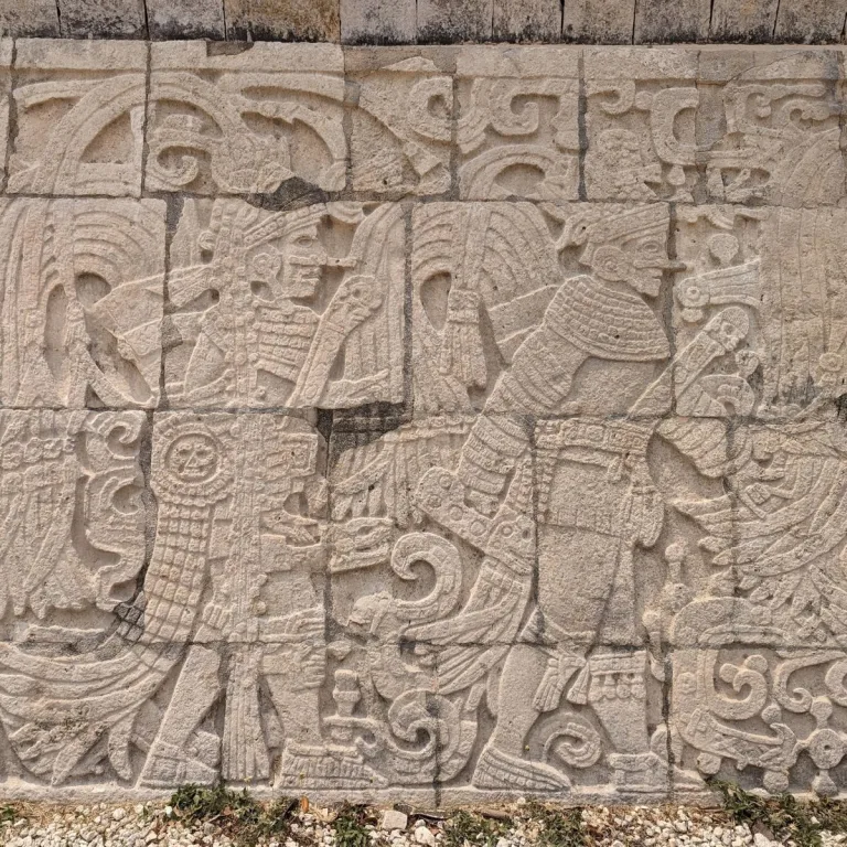 Carved warrior relief on the Platform of the Eagles and Jaguars at Chichén Itzá in Yucatán, Mexico, showing two elaborately dressed figures in limestone.