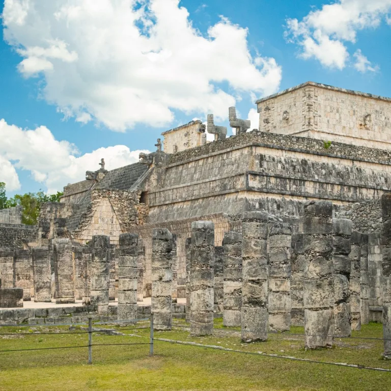 Temple of the Warriors at Chichén Itzá in Yucatán, Mexico, with rows of stone columns in the foreground and the temple’s stepped platform behind them.
