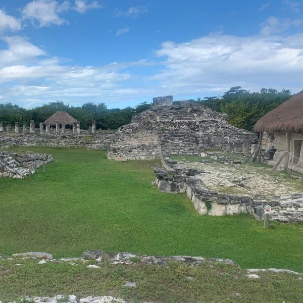 A wide view of Structure 2 at El Rey shows its stepped pyramidal platform, surrounding foundations, and nearby columned buildings.