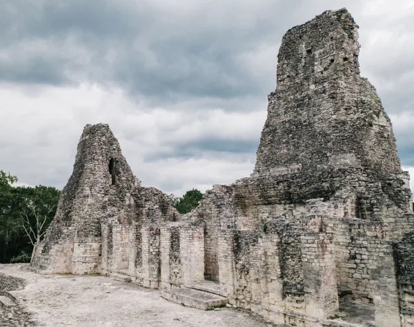 Structure I-1, the Building of the Three Towers at Xpuhil in Campeche, Mexico, with two of its tall Río Bec-style masonry towers visible beneath a cloudy sky.