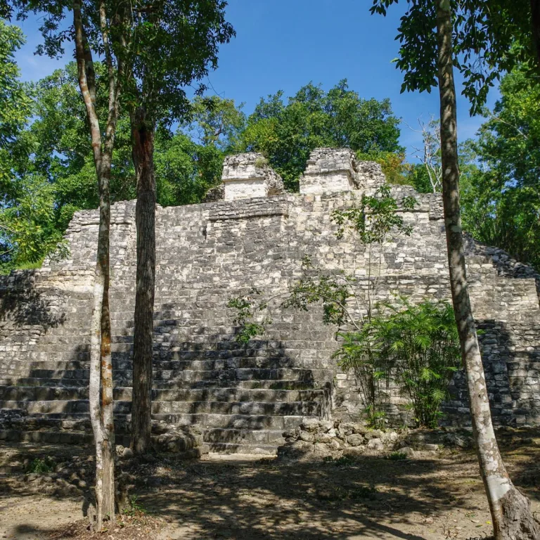 Edificio D5-5 at Balamkú in Campeche, Mexico, showing a broad central limestone staircase ascending a monumental Maya pyramid with partially preserved temple walls at the summit.