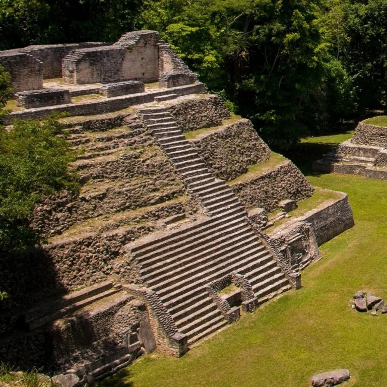 Structure B20 on Caana at Caracol in Cayo District, Belize, showing a steep central staircase, stepped terraces, sculpted masks beside the lower steps, and ruined summit rooms.