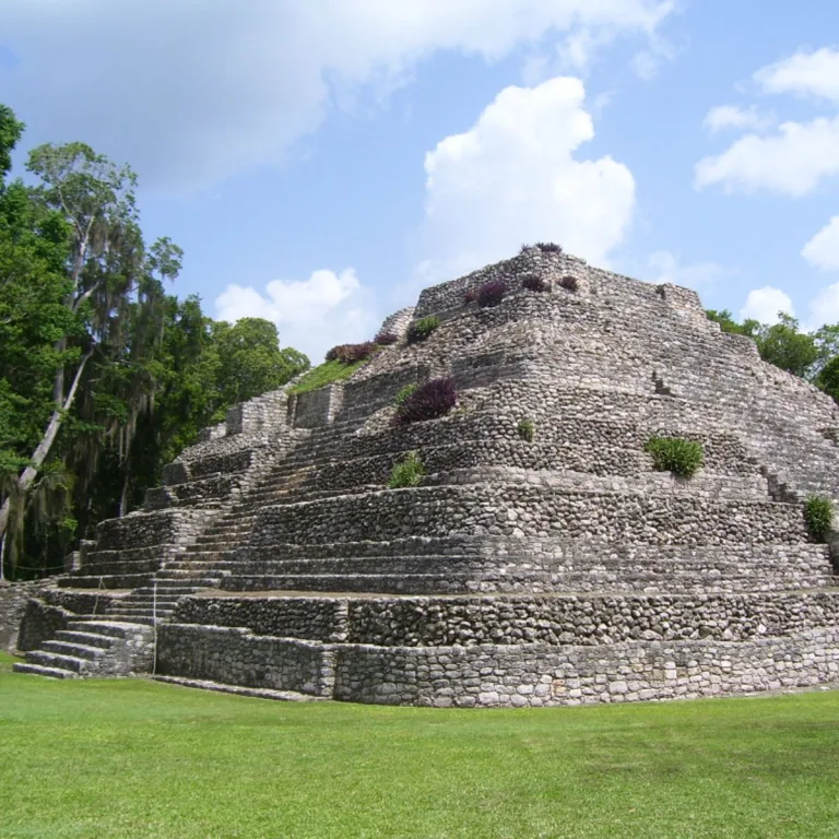 Edificio 24 at Chacchoben in Quintana Roo, Mexico, showing the stepped Maya pyramid with rounded Petén-style corners beside Plaza B.