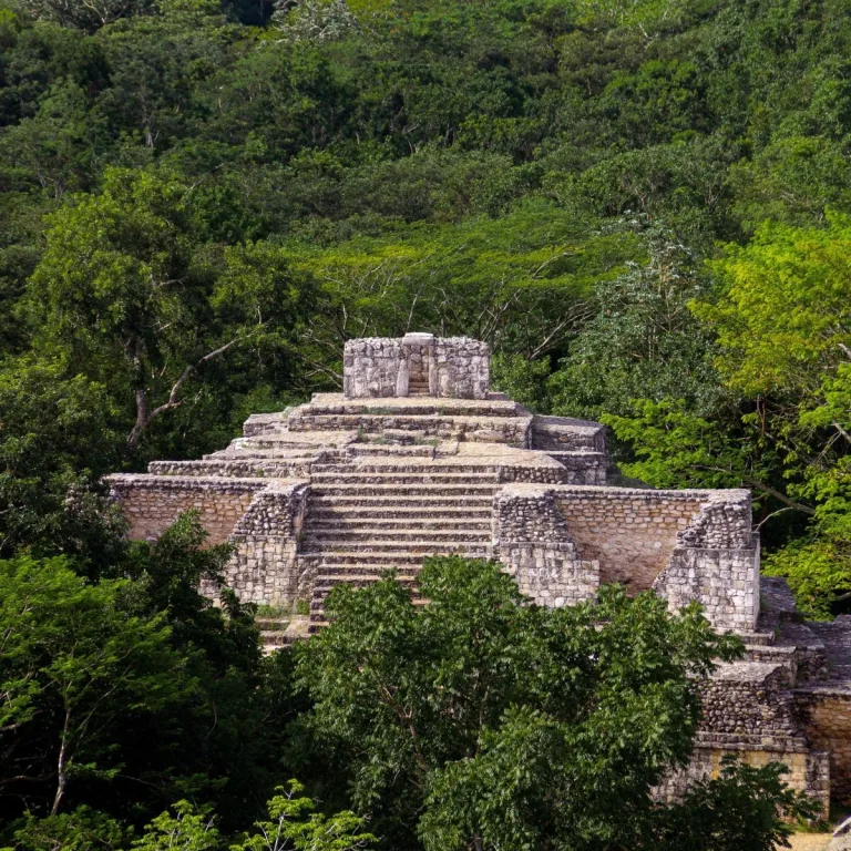 Structure 16, the Oval Palace at Ek Balam in Yucatán, Mexico, rises above the surrounding trees with a central stairway leading to its upper room.